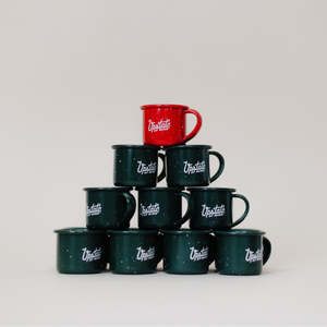 A stacked triangle of our heritage mug ornaments that form a shape of a Christmas tree. The first three stacks have all green mug ornaments, and a single red one is on the top. All mini mugs have "Upstate of Mind" text in white on the front.