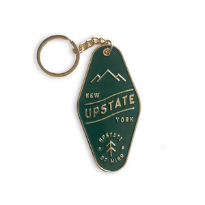 Upstate Motel Key Keychain in Forest Green. Chain, keyring, and raised text/illustrations are golden. Text reads: "UPSTATE, NEW YORK / Upstate of Mind".