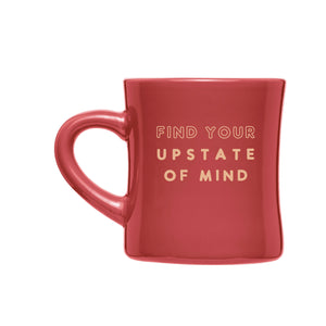 A product photo of The Upstater Ceramic Diner Mug. Mug is red with a tan graphic design of text that reads "Find your Upstate of Mind" in the middle.