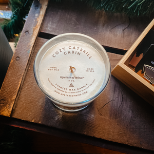 Photo of Cozy Catskill Cabin Candle - 9oz, on top of a rustic wooden box.