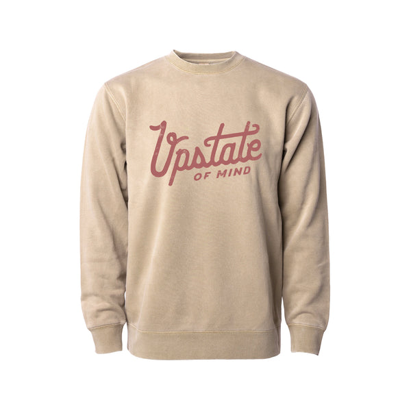 Upstate of Mind - Heritage Script Crewneck - Sandstone Wash. This crew neck is a super comfy, pigment-dyed fleece that is designed for comfort.  Soft hand feel print on a vintage washed sweatshirt.  Graphic reads "Upstate of Mind" in a large heritage script text.